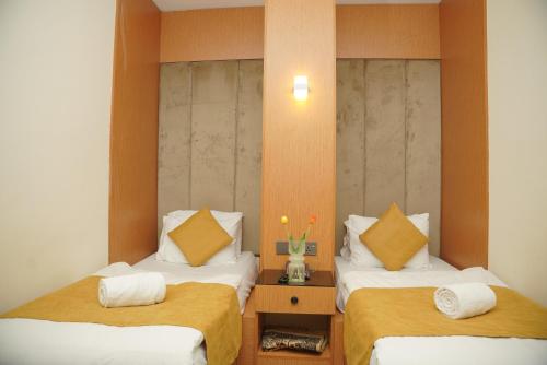 a room with two beds with white sheets and yellow pillows at MyHotel Erbil in Erbil
