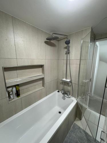 La salle de bains est pourvue d'une baignoire blanche et d'une douche. dans l'établissement Charming 4 Bed House, 20 Minutes to Central London, à Edgware