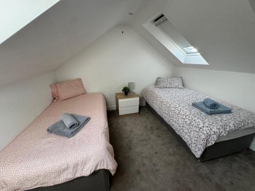 Cette chambre mansardée comprend 2 lits jumeaux et une fenêtre. dans l'établissement Charming 4 Bed House, 20 Minutes to Central London, à Edgware