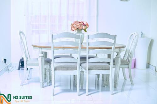 a dining room table and chairs with a vase of flowers on it at N3 Luxury Suite in Mzuzu