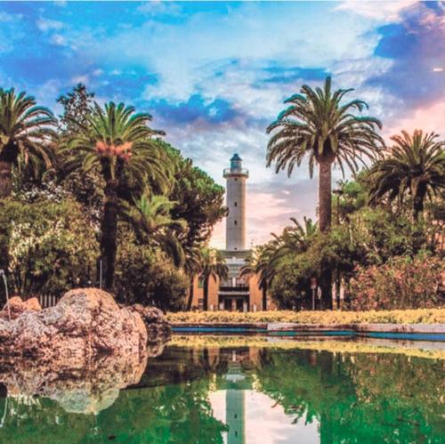 a building with a clock tower and a pond with palm trees at Acasadelpescatore in San Benedetto del Tronto