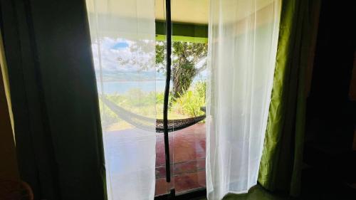 a window with a view of a hammock outside at Lake Arenal Brewery & Hotel in Tilarán