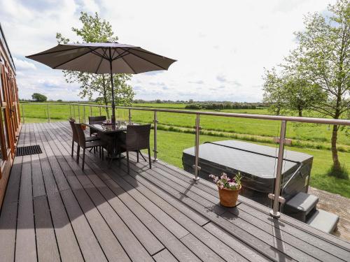 a wooden deck with a table and an umbrella at Holmside in Market Drayton