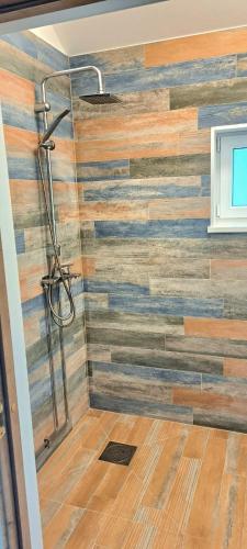 a bathroom with a shower with a wooden wall at Jūrmalciema Namiņi in Jūrmalciems