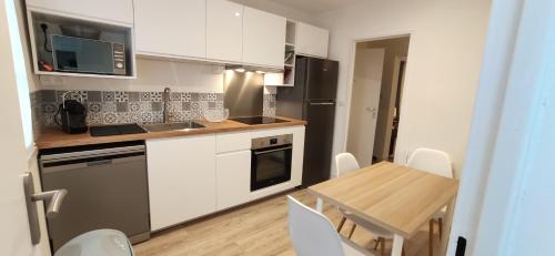 une cuisine avec des armoires blanches et une table avec des chaises dans l'établissement Appartement T4 Bayonne, à Bayonne
