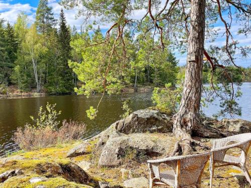 a bench sitting next to a tree next to a lake at 4 star holiday home in Mellösa-By Traum in Mellösa