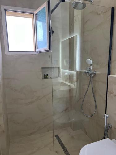 a bathroom with a shower with a glass door at Apartments Rezidenca Sinani Orikum in Orikum