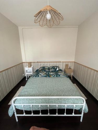 a bedroom with a bed and a chandelier at Maison coeur des Weppes La Maralbique in Wavrin