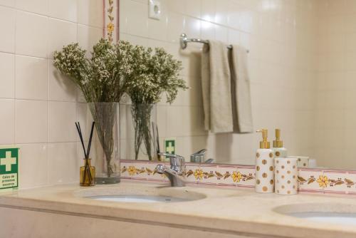 Sun e Sea Golf House في Aroeira: حمام مع مغسلتين مع إناء من الزهور