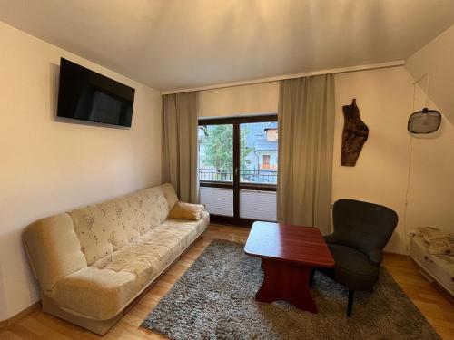a living room with a couch and a table and a window at Apartament pod Doliną - 1,5km. od Krupówek in Zakopane