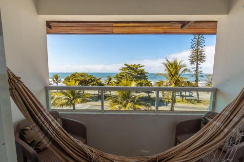 a hammock in a room with a view of the ocean at Hotel VillaReal Guaratuba - Caieiras in Guaratuba