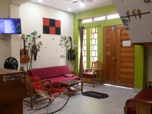 a living room with a red couch and a guitar on the wall at Moicca Youth Hostel in Iquitos