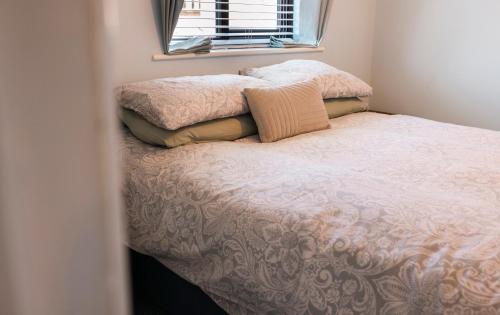 1 dormitorio con 1 cama con 2 almohadas y ventana en THE COSY HOME BY KS - Free Parking, WI-FI, Smart TV, Kitchen, Washing machine, Long Stays Welcomed, en Hereford
