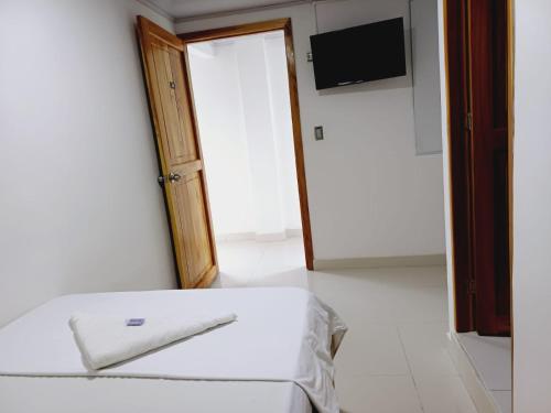 Schlafzimmer mit einem weißen Bett und einem TV in der Unterkunft HOTEL VINCCI in Chigorodó