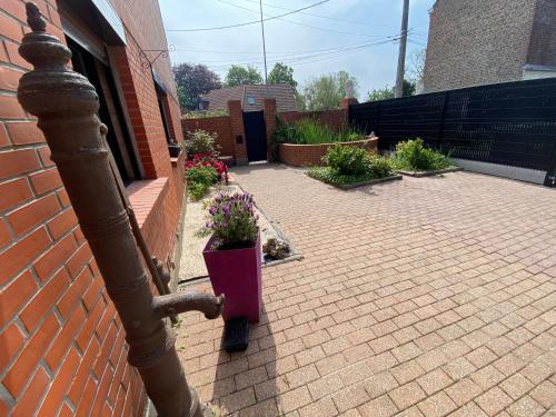 a brick patio with a potted plant on the side of a building at Maison coeur des Weppes La Maralbique in Wavrin