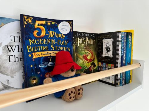 a book shelf with a teddy bear and books at Sea Walk Cottage, Milford On Sea in Milford on Sea