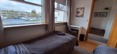 a bedroom with a bed in front of a window at Private room, close to a swimming pool in Reykjavík