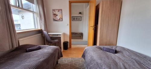 um quarto com 2 camas, uma janela e uma cadeira em Private room, close to a swimming pool em Reykjavík