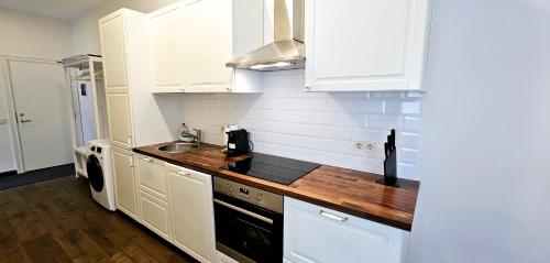 a kitchen with white cabinets and a wooden counter top at Villa Loebel 1881 in Juodkrantė