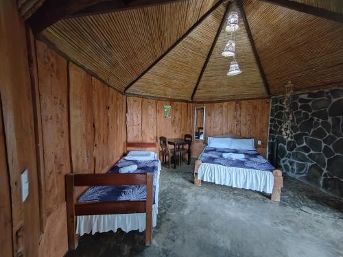 - une chambre avec 2 lits dans une cabane en bois dans l'établissement Hotel, Restaurante y Mirador Bosque Alegre, à Río Cuarto