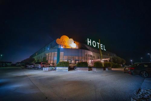 a hotel building with a lit up sign at night at LifeHotel Vienna Airport in Fischamend Dorf