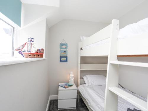a small bedroom with a bunk bed and a bedside table at Ty Bara in Cemaes Bay