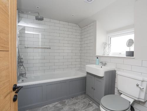a bathroom with a tub and a toilet and a sink at Ty Bara in Cemaes Bay