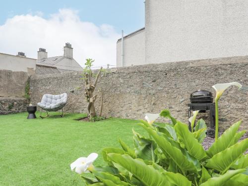 a garden with a chair and a grill next to a wall at Ty Bara in Cemaes Bay