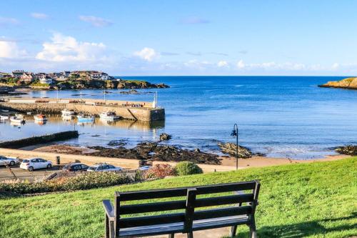 a bench sitting on a hill overlooking a body of water at Ty Bara in Cemaes Bay