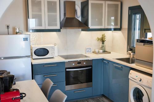a kitchen with blue cabinets and a microwave at Sand Lily Villa Mykonos in Mýkonos City