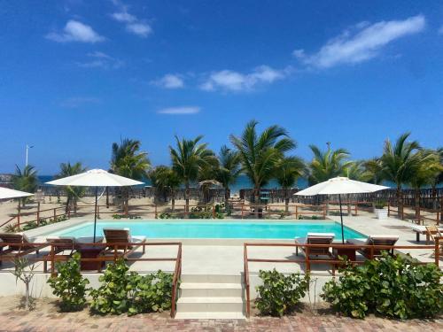 una piscina con sedie, ombrelloni e palme di El Samay Hotel Boutique a Canoas De Punta Sal