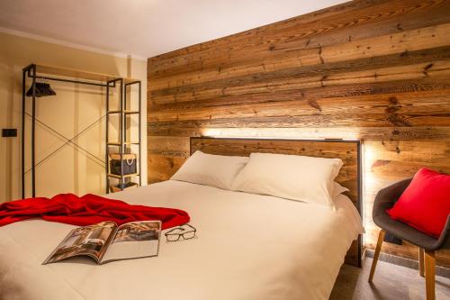 a bedroom with a white bed with a wooden wall at Apartments Les Crouses in Valtournenche