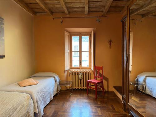 a room with two beds and a window and a red chair at Casale Brambilla in San Zenone al Po