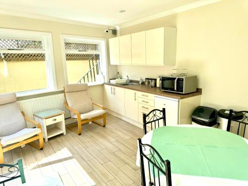 a kitchen with a table and chairs and a microwave at Lavender Guest House in London
