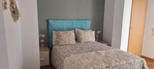 a bedroom with a bed with a blue headboard and pillows at Apartamentos AD in Villanueva de Arosa