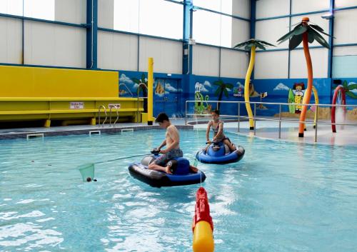 two people riding on tubes in a swimming pool at Golden Anchor - The Vogue - Coastal Caravan Breaks in Chapel Saint Leonards