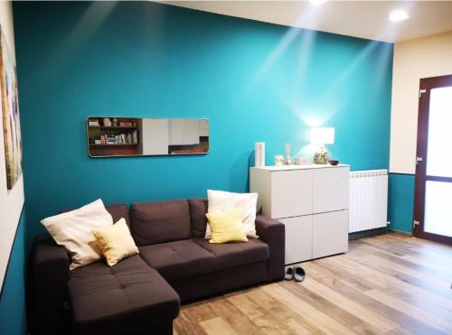 Una sala de estar con un sofá y una pared azul. en Casa Camilla, en Grosseto