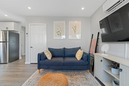 a living room with a blue couch and a refrigerator at The Garden Retreat in Welland, On - 1BR,Free Parking and Workspace in Welland