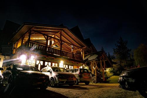 a log cabin with cars parked in front of it at night at Gabrysiówka in Tylka