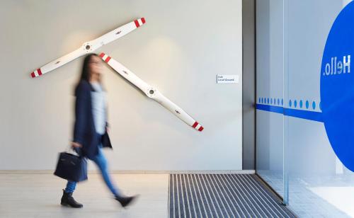 a woman walking in front of a wall with a sign at Holiday Inn Express Sydney Airport by IHG in Sydney