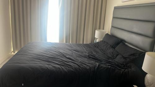 a bedroom with a bed with a black comforter and a window at Impeccable 1-Bed Apartment in Barking