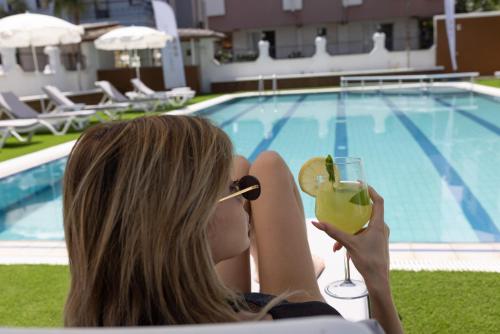 a woman holding a drink in front of a pool at Three Points Hotel in Beldibi