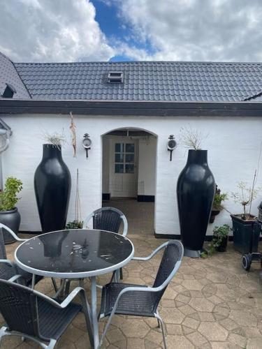 a patio with a table and chairs and two large vases at Nedlagt Landbrug med 3 lejligheder in Vejle