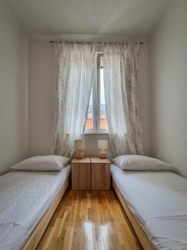 two beds in a room with a window at Sea View Apartment No3 Kaštela in Kaštela