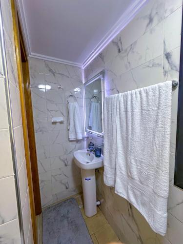 a white bathroom with a sink and a mirror at VELUXA - LUXURY HOLIDAY HOMES - Centric flat in Tangier