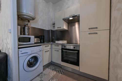 une cuisine avec un lave-linge et un micro-ondes dans l'établissement Séjour à la source - Opéra, casino, kiosque, à Vichy