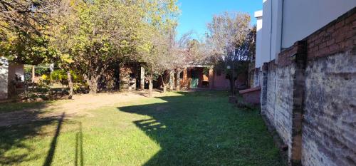 un patio con árboles y una pared de ladrillo en Casa En Cura Brochero Para Una Familia De 5/6 Pers. Todas las comodidades en Villa Cura Brochero
