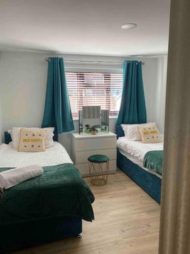 a bedroom with two beds with blue curtains at Rockley Green House - 3 Bedroom Home in Liverpool in Liverpool