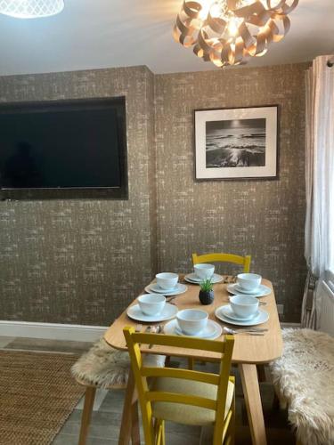 a dining room with a table with chairs and a television at Rockley Green House - 3 Bedroom Home in Liverpool in Liverpool