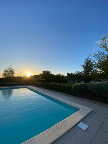 - une piscine avec vue sur le coucher du soleil en arrière-plan dans l'établissement Les Gites de Yanaely - Primel, à Juignac
